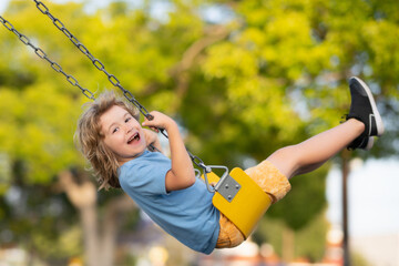 Outdoor playground. Funny kid on swing. Little boy swinging on playground. Happy cute excited child on swing. Cute child swinging on a swing. Crazy playful child swinging very high. - obrazy, fototapety, plakaty