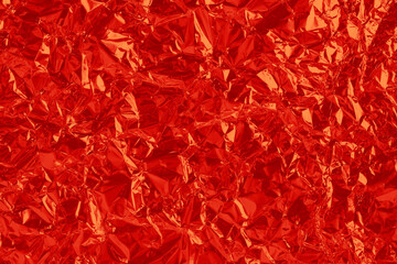 Shiny dark red foil texture background, pattern of wrapping paper with crumpled and wavy.