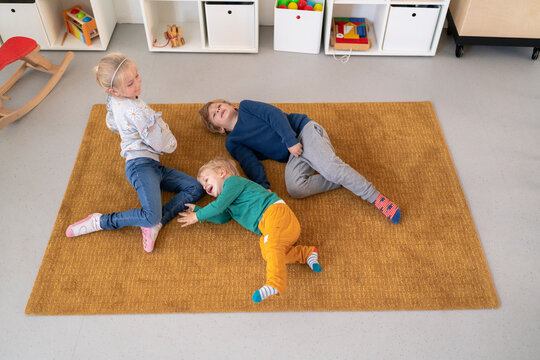 three kids laying on carpet