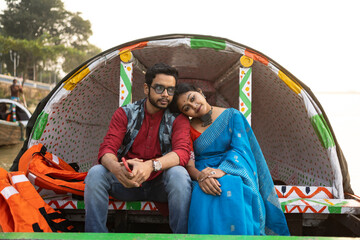 Romantic couple sit together on a boat floating over riven Ganges