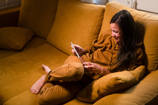Woman laughing on sofa during tablet video call