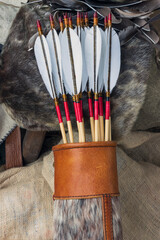 Leather bow quiver filled with arrows with graven wood nocks and traditional natural fletching,...