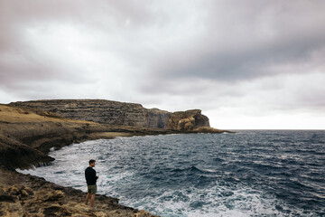 Man looking at the cliffs where the Azure Window of Malta was