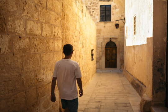 Young man walking through the medieval town Mdina in Malta