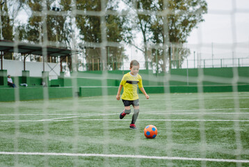 Little boy dribbling football