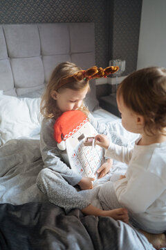 Kids open Christmas advent calendar in bed