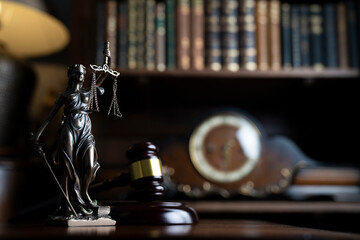 Fototapeta na wymiar Law theme. Judge chamber. Judge’s gavel, Themis sculpture, scale and collection of legal books on the brown desk.