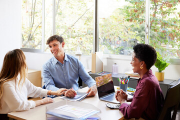 Positive couple discussing mortgage contract in office