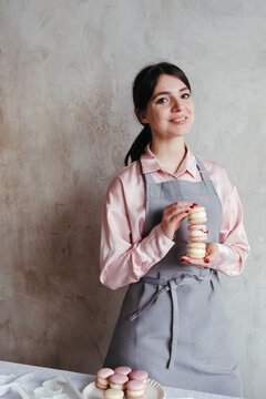 Female pastry chef with macarons in hands.