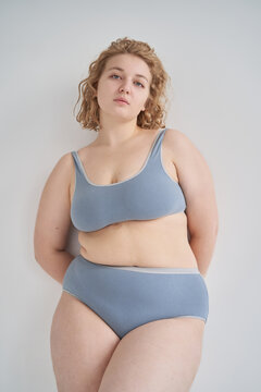 Graceful plus size lady in underwear leaning on wall