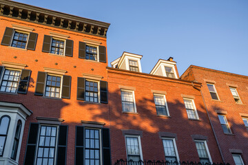 An old brick building with tall windows and residential attic space in Cambridge in New England
