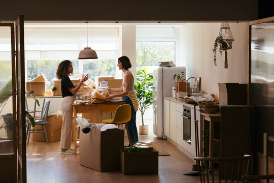 Happy diverse women unpacking groceries in kitchen