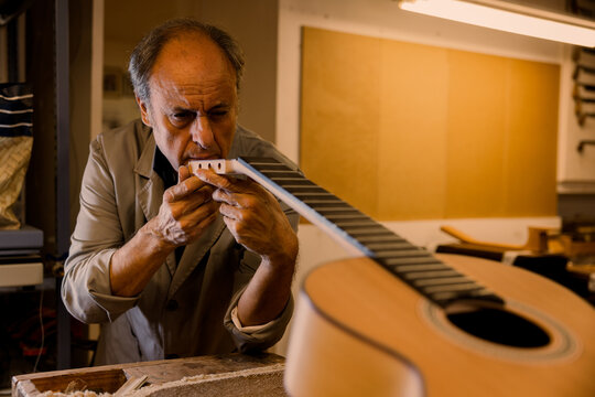 Focused luthier working in workshop with a classic spanish guitar