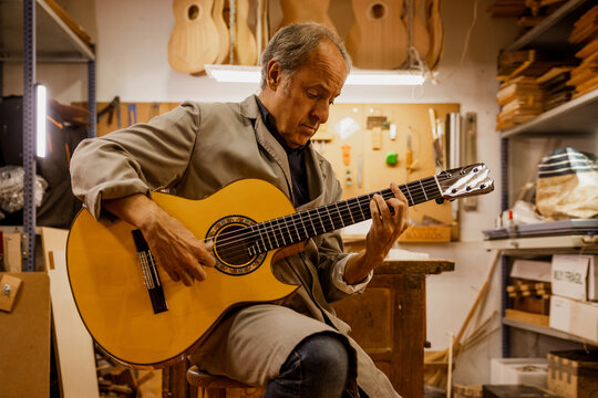 Luthier testing a finished custom classical guitar