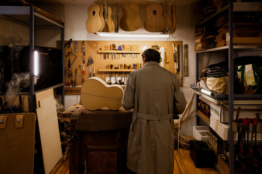 Concentrated luthier from behind working in workshop