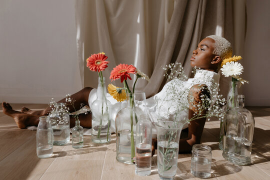 Graceful woman lying on floor near vases in light room