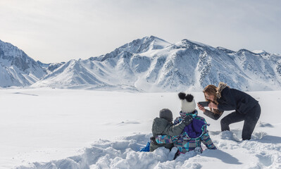 Mother taking photos of her two kids in the snow