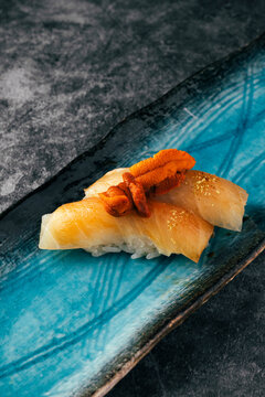 Delicious nigiris of lemon fish and sea ââurchin on blue plate