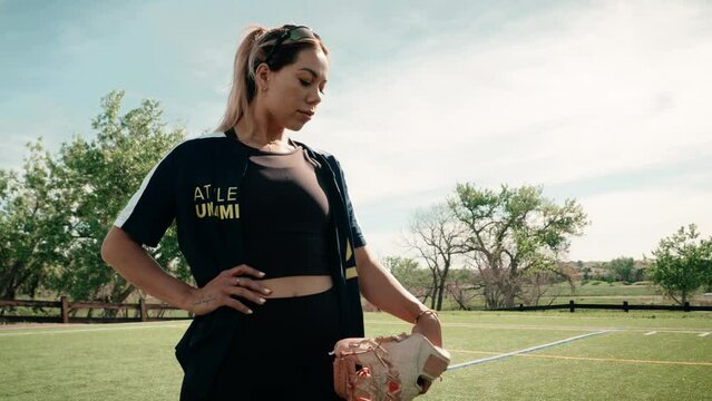 Beautiful female softball athlete strikes a dramatic pose standing still as she holds her glove next to her fit body.  Shot in hd 4k as well as glorious slow motion.