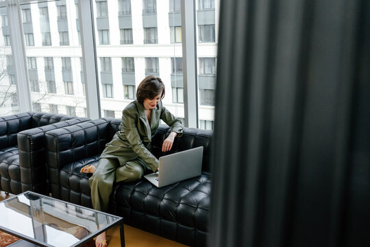 Woman In Green Leather Suit Using Laptop On Couch