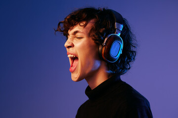 Man singer wearing headphones listening to music and singing with his mouth open, recording studio,...