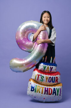 Cute girl with big ballon of number 9 and a birthday cake