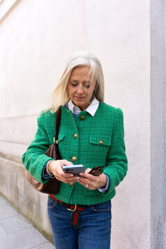Sophisticated Woman With Green Jacket Using The Phone Outdoors.