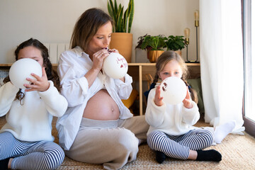 Pregnant mom and children blowing up baby showers balloons 