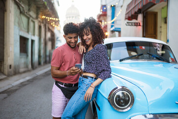 Stylish car with phone near vintage car on street