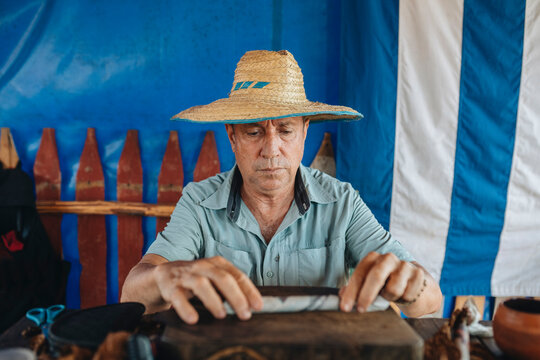 Elderly man in straw hat rolling cigar