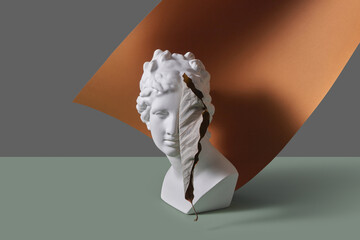 Greek sculpture with leaf on brown paper sheet.