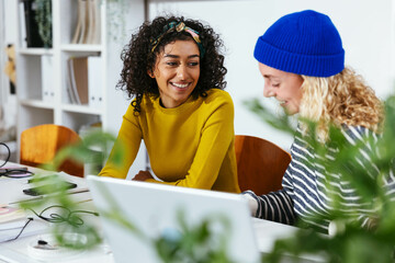 Smiling colleagues with laptop in office