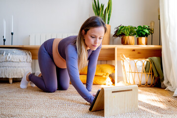 Pregnant woman prepares exercise routine using tablet at home