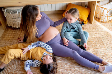 Pregnant woman relaxing with her daughters after exercises 