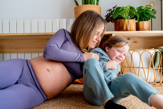 Pregnant mom tickling her daughter at home