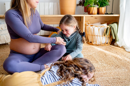 Pregnant woman relaxing with her daughters at home