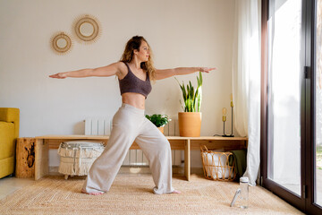 Pretty woman doing yoga at living room 