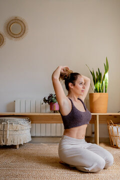 Woman fixing her hair before her yoga practice at home