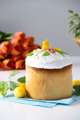 Traditional Easter cake with marshmallow glaze and spring decoration, orange tulips on background. Happy Easter. Recipe of Easter bakery. Festive pastry for spring holidays.