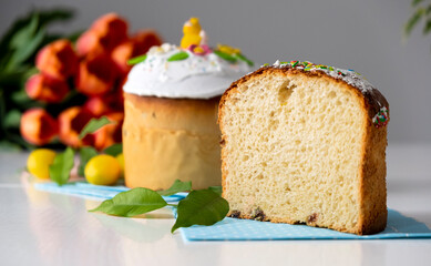 Traditional Easter cake with white icing and spring decoration, orange tulips on background. Happy Easter. Recipe of Easter bakery. Festive pastry for spring holidays.