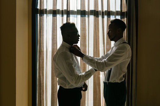 Black groom and best man near window