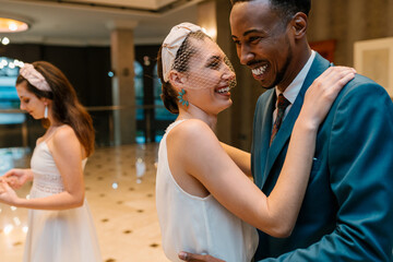 Multiracial newlyweds laughing during dance