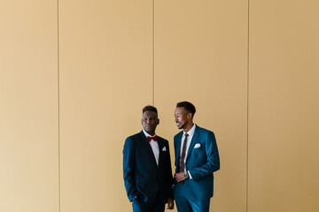 Black men in suits talking near wall