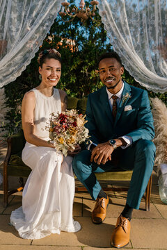 Multiracial bride and groom looking at camera