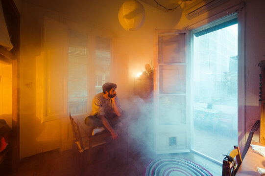Surreal portrait of sitting man in burning home