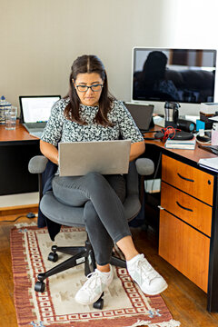 Woman sitting in home office working remotely with a laptop