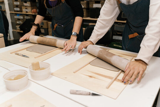 Crop masters molding clay pieces with rolling pins