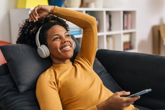 Beautiful African American woman is listening to music using headphones