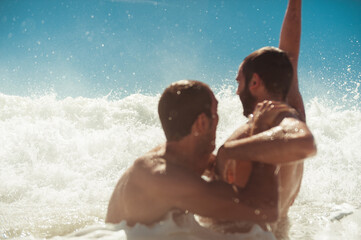 Two friends having fun playing with sea waves