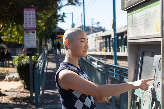 Gen Z woman buys metro ticket outside train stop